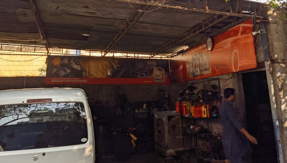 Service bay at Safdar Auto Workshop with Shell banners and a rack of lubricants