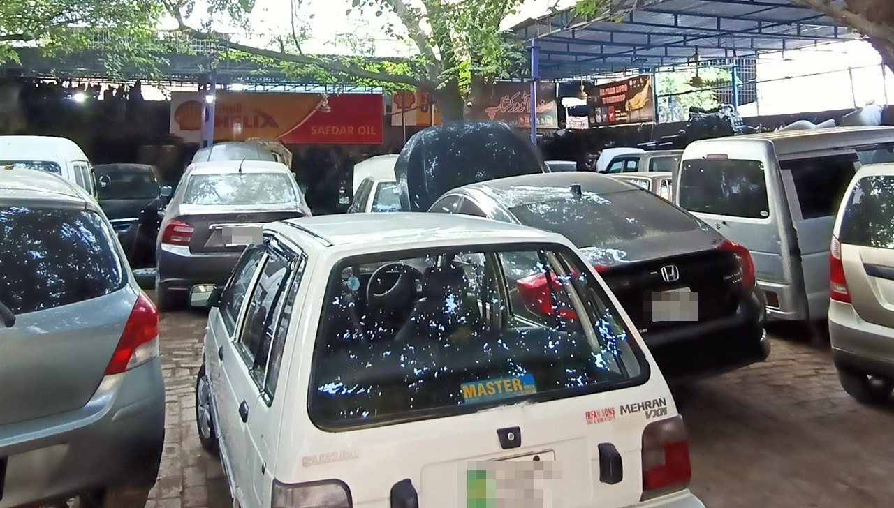 Customer cars in the Safdar Auto Workshop yard under a Shell Helix banner